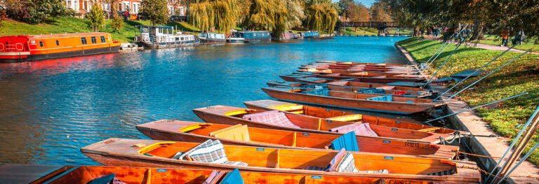 Punting boats on the River Cam, Cambridge. Scenic river view with boats and canal boats. Cambridge tourism.