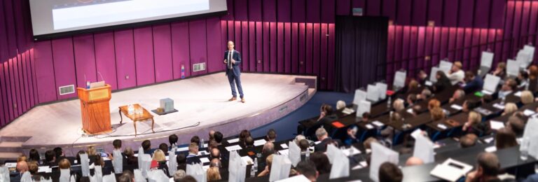 Conference meeting full page: Speaker on stage at business conference addressing audience.